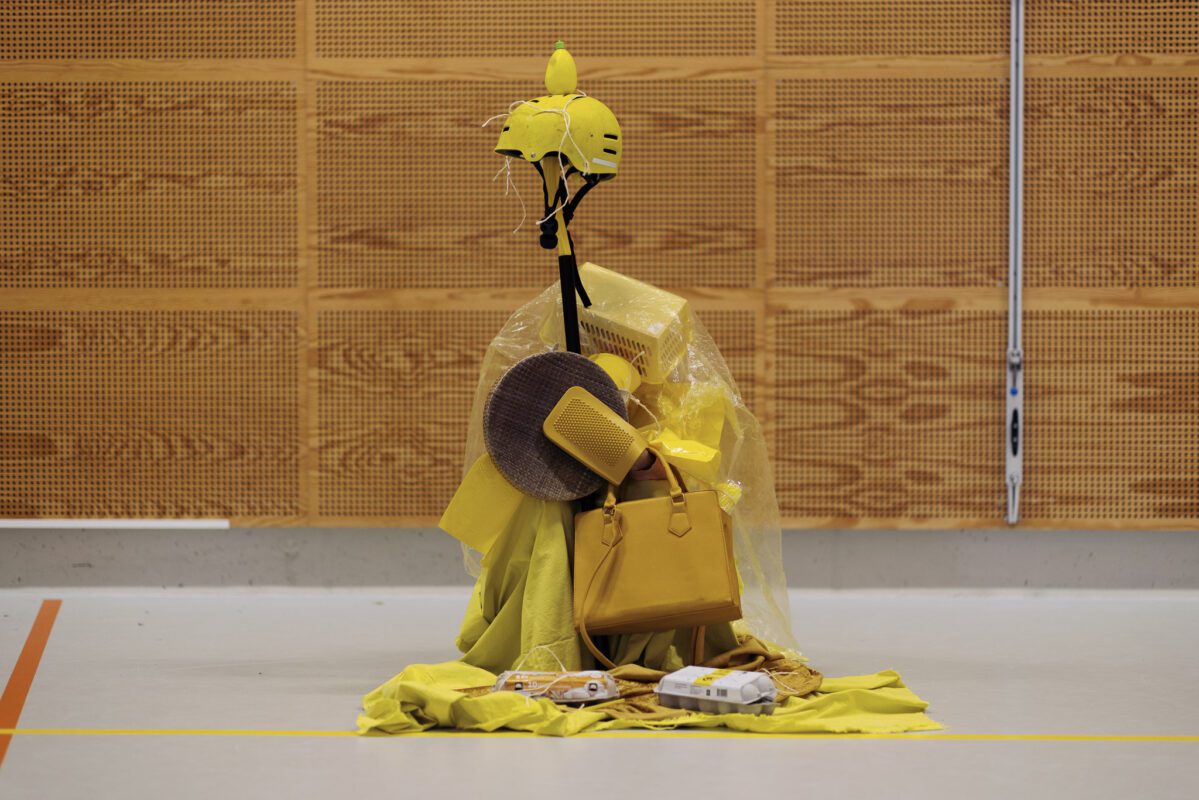 Een kind is verkleed als levende kunst bestaande uit allerlei gele voorwerpen