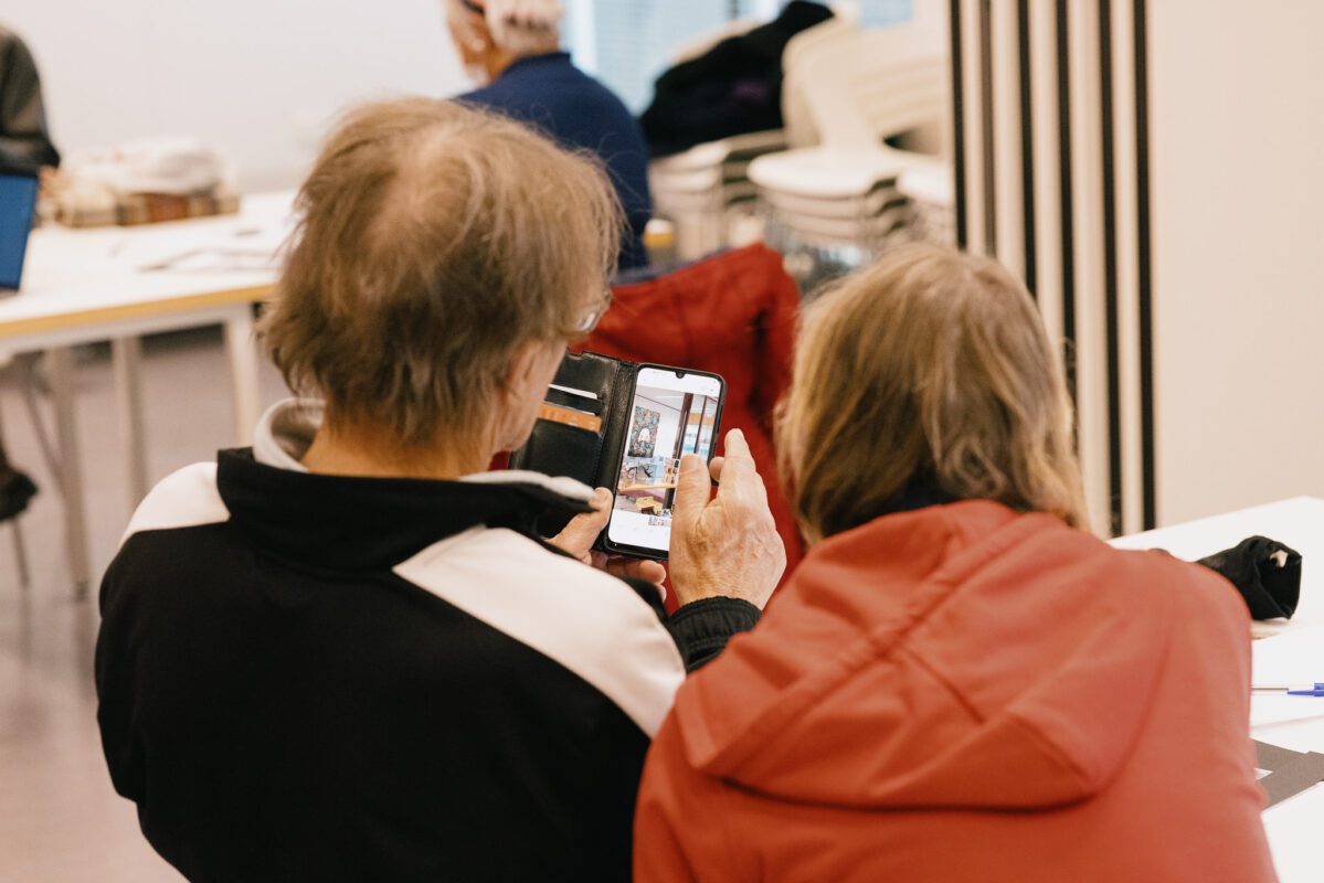 Twee deelnemers winterschool werken samen aan een fotografieopdracht op mobiele telefoon