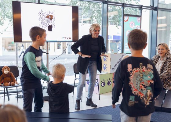 Foto door Robin Butter waarbij je een docent op een voor een scherm ziet en kinderen doen haar na